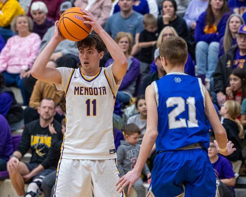 Mendota's Aden Tillman (11) holds ball over-head looking for pass whilst being guarded by Newman's Brandt Camper (21) on Friday, January 30, 2026 at Mendota High School in Mendota.