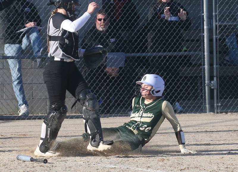 St. Bede's Quin McClain slides into home as Woodland/Flanagan-Cornell catcher Ella Derossett waits for the late throw on Tuesday, April 8, 2025 at Woodland High School.