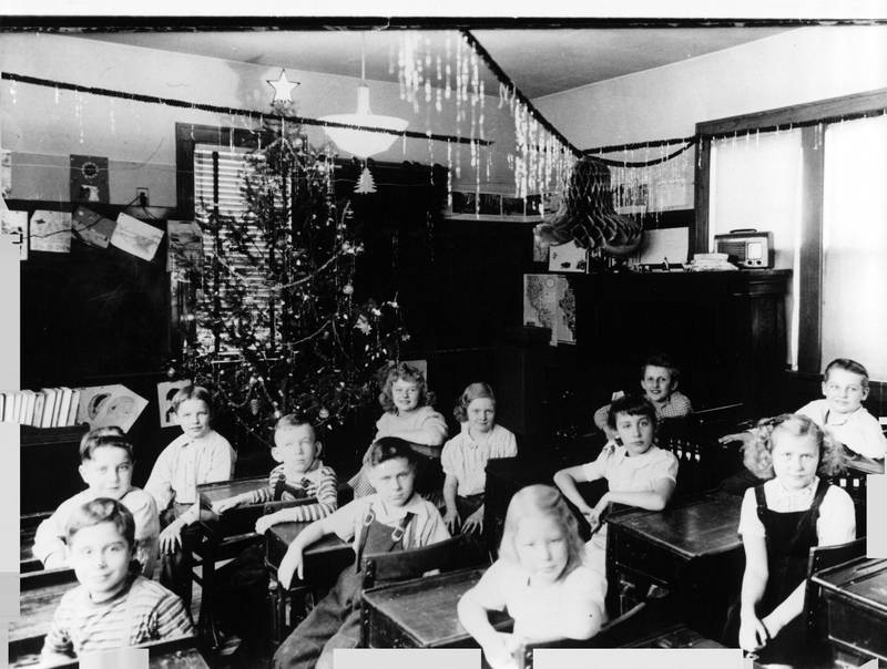 Students pose for a photo in Cronin Schoolhouse in 1946 amidst the schoolhouse's Christmas tree and decorations.
