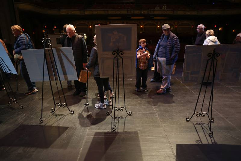 Guest looks at the poster boards on display on the stage at the Rialto Theater’s 100th anniversary celebration on Sunday, May 3, 2026 in Joliet.
