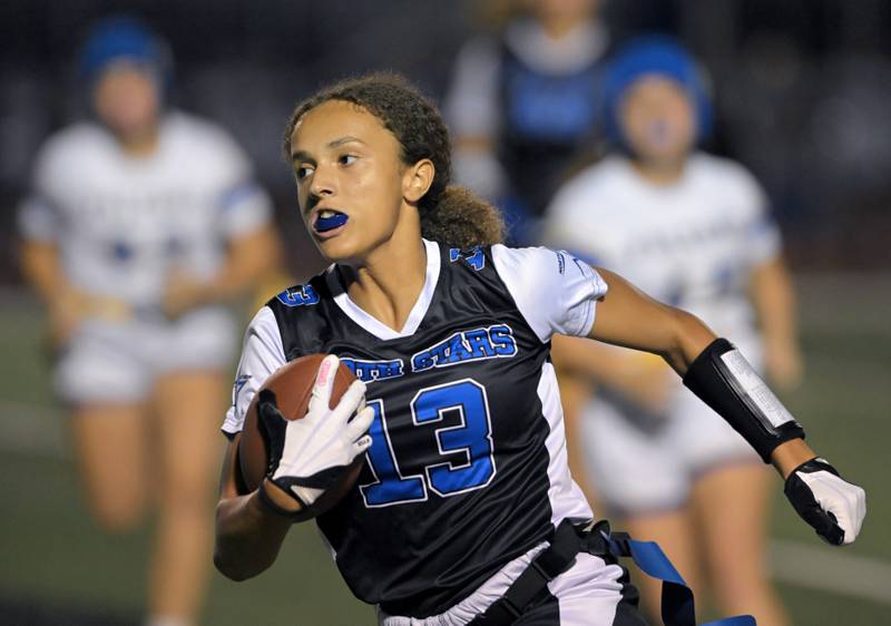 St. Charles North’s Alexandria Richardson runs away from Wheaton North defenders in a girls flag football game in St. Charles on Monday, Sept. 15, 2025.