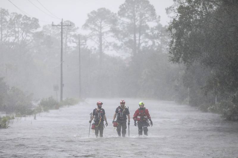 Rescue workers with Tidewater Disaster Response wade through a tidal surge on SW 358 Highway while looking for people in need of help after the Steinhatchee River flooded on Wednesday, Aug 30, 2023, in Steinhatchee, Fla., following the arrival of Hurricane Idalia. (Douglas R. Clifford/Tampa Bay Times via AP)