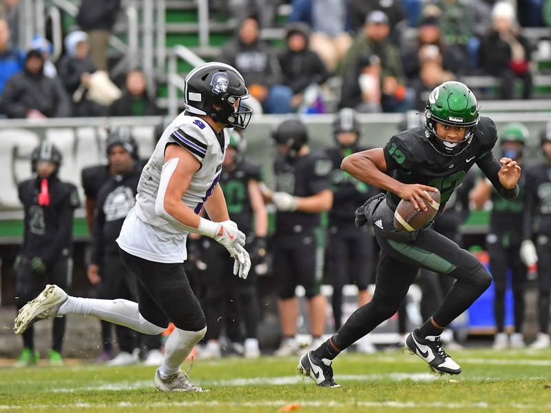 Glenbard West quarterback AJ Rayford (right) tries to scramble away from Downers Grove North’s William Vala during a Class 7A second-round playoff game on November 8, 2025 at Glenbard West High School in Glen Ellyn.