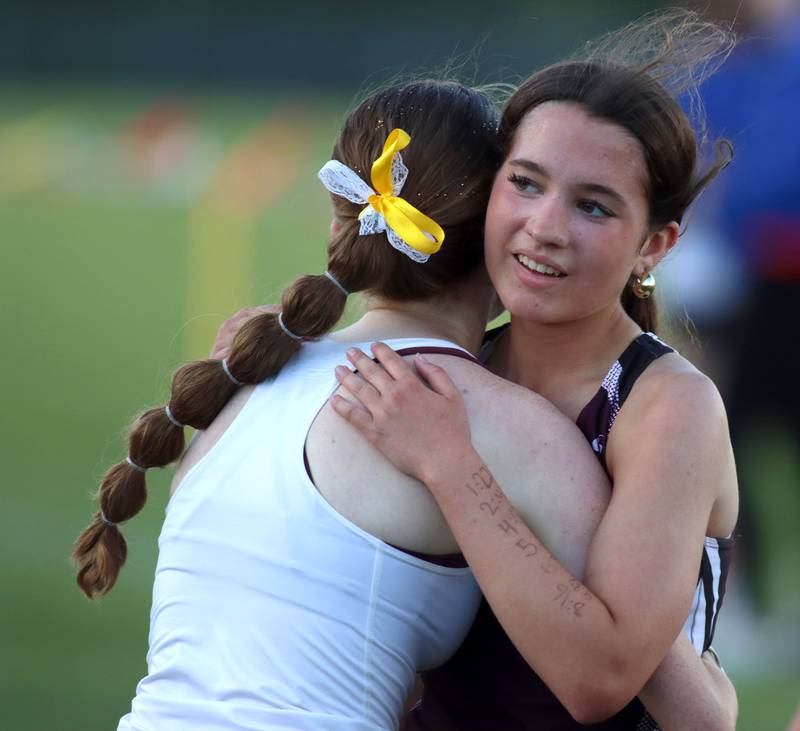 Carmel’s Izzy Bing, left, hugs Prairie Ridge’s Emaline Foster after the finish of the 3200-meter run in IHSA Class 2A Girls Sectional Track action at Genoa-Kingston School in Genoa on Friday, May 16, 2025.