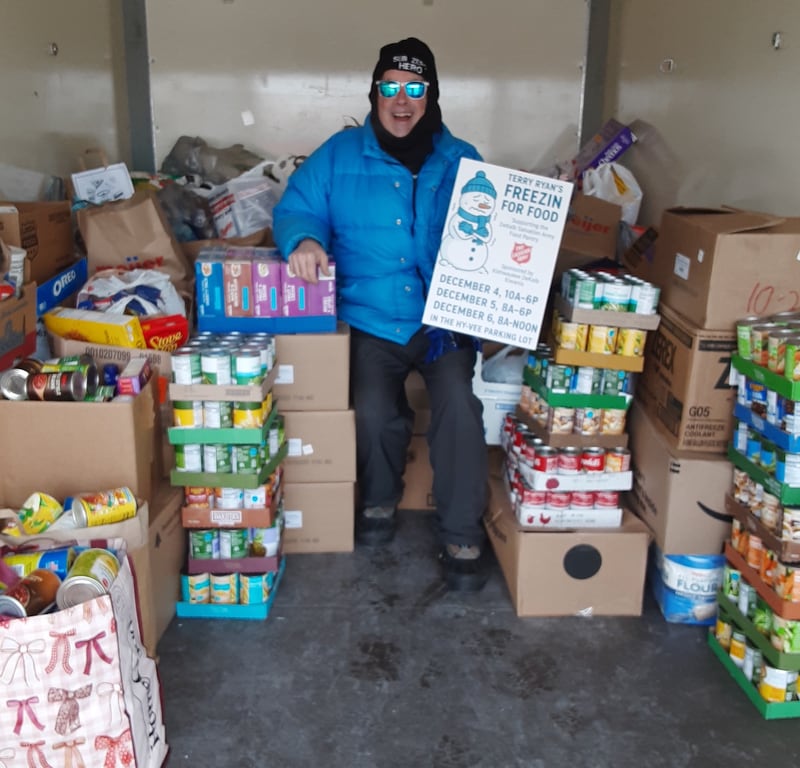 Former DeKalb radio host turned podcaster TD Ryan poses with stacks of donated food on Friday, Dec. 5, 2025, at Ryan's annual Freezin' For Food collection drive in the parking lot of Hy-Vee in Sycamore. The collection raises funds and donations for The Salvation Army to help feed families this holiday season.