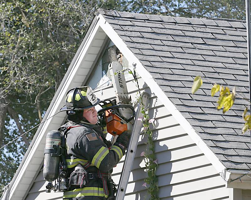 A Wallace firefighter uses a chainsaw to vent the roof of a attic at a home located at 1529 Sycamore Street on Monday, Oct. 3, 2022 in Ottawa. The house fire began shortly before 2p.m.