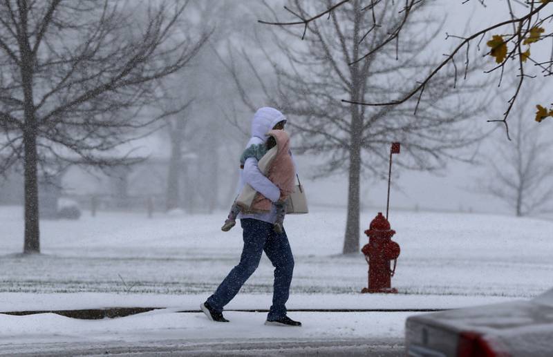 Joyce Becker carries her granddaughter, Anna McIntyre, 2, through the snow to their car on Thursday, Nov. 21, 2024, in the parking lot of McHenry Recreation Center as winter weather makes its first appearance in McHenry County.