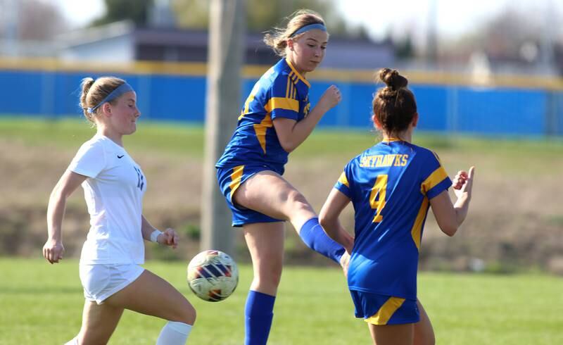 Johnsburg’s Gabriella Kay, center, moves the ball past Woodstock’s Kendall Pope, left, in varsity soccer on Wednesday, April 23, 2025, at Johnsburg High School in Johnsburg.