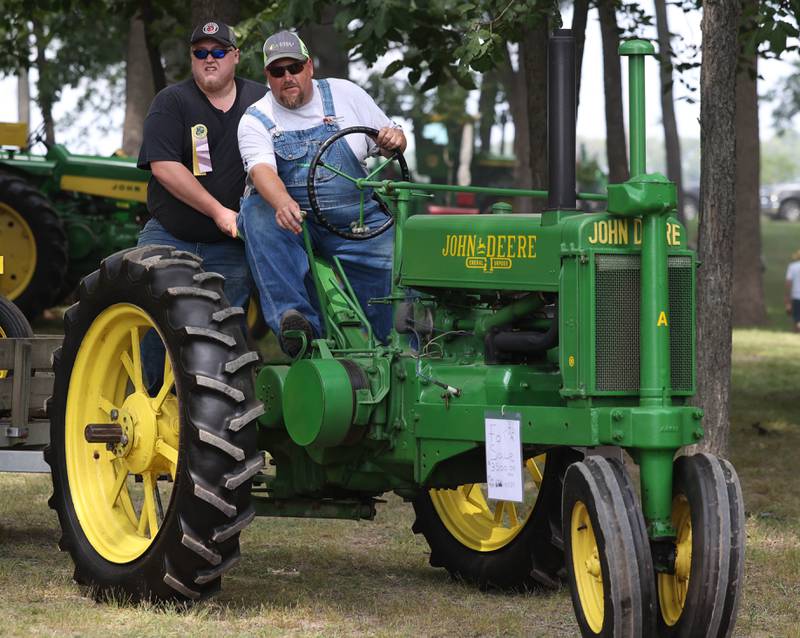 Jeremy Luse, (left) from Machesney Park, and Max Wilson, from Harvard, ride atop a John Deere A tractor Thursday, Aug. 7, 2025, at the 68th annual Sycamore Steam Show and Threshing Bee at Taylor Marshall Farm on Lukens Road in Sycamore.