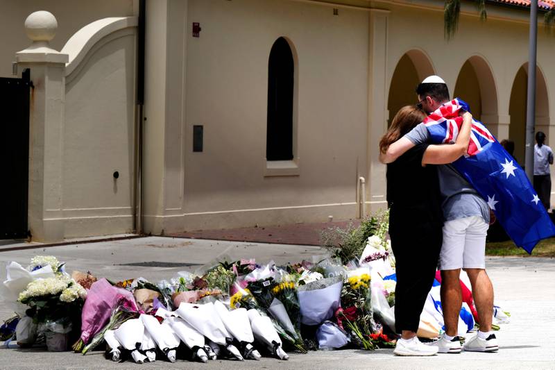 A couple lay flowers at a tribute to shooting victims outside the Bondi Pavilion at Sydney's Bondi Beach, Monday, Dec. 15, 2025, a day after a shooting. (AP Photo/Mark Baker)