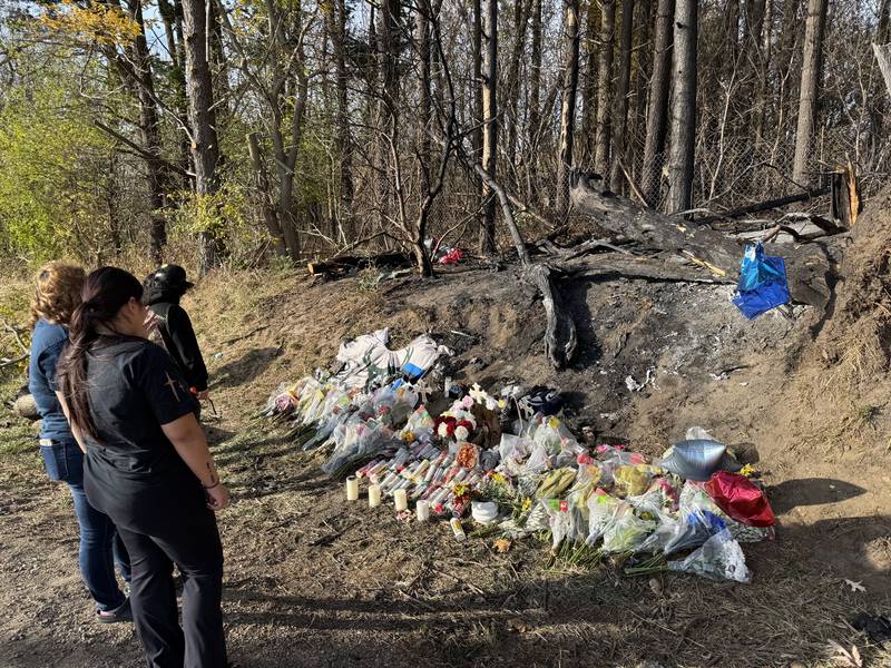 People gather on Tuesday, Oct. 29, 2024, at the site of a crash that claimed three lives near Woodstock two days before.