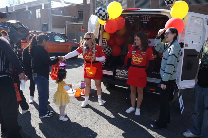 A family collects candy at the Lightning McQueen vehicle at the Joliet Police Department Trunk-Or-Treat event on Saturday, Oct. 26, 2024 in Joliet.