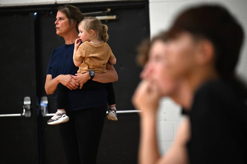 Kankakee Trinty Academy's Head Boys Volleyball Coach Chrissy Hathaway shows how resourceful a grandmother can be while holding grandchild Harper Seyden, 2, during the game against Manteno on Thursday, May 1, 2025.