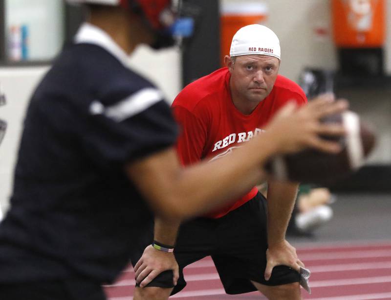 Huntley’s new coach Mike Naymola watches his team run a play during the first day of football practice Monday, 8, 2022, in the Huntley High School  field house after stormy weather move practice inside.
