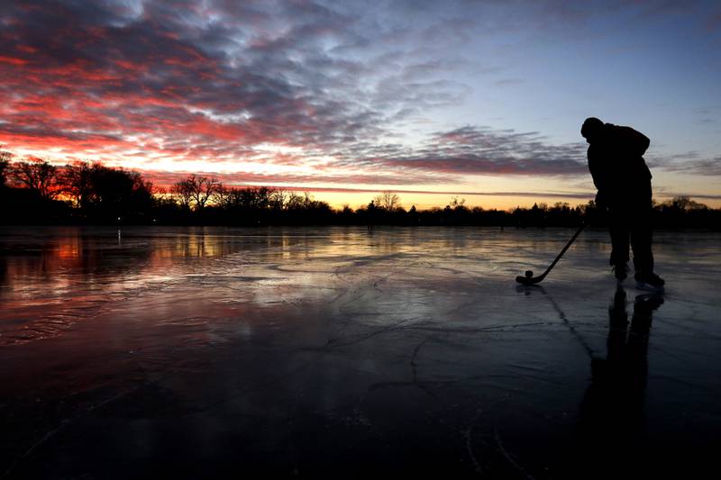 River Hudon controls the puck while skating and pass a hockey puck with his dad, Rick, on Wednesday, Jan. 8, 2025, on Crystal Lake near West Park.