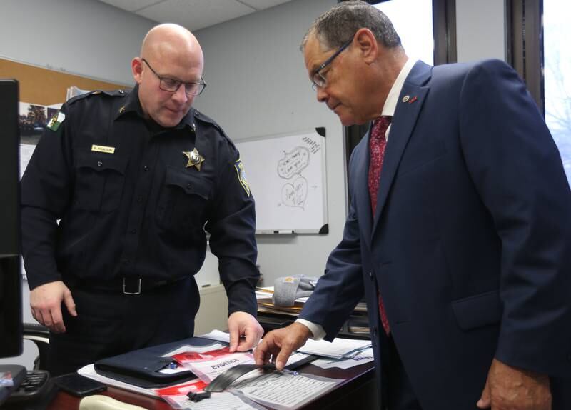 Ottawa Police Chief Brent Roalson (left) and La Salle County State's Attorney Joe Navarro examine a disabled GPS monitoring device Wednesday, Nov. 27, 2024, at the Ottawa Police Station. A growing number of felony suspects, they say, are disabling or cutting off their ankle bracelets in open defiance of the terms of pre-trial release.