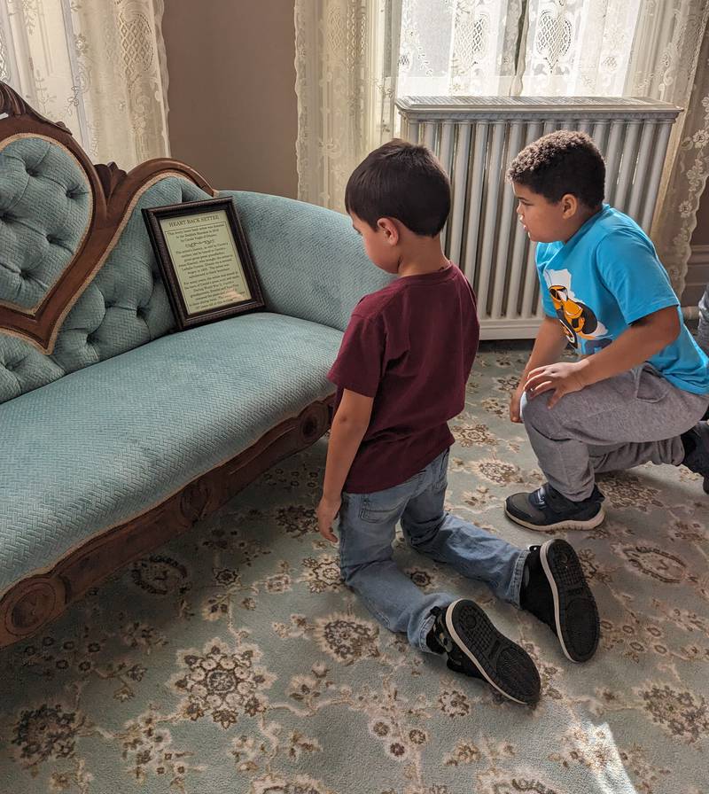 Two Grand Ridge second graders read the story about the antique settee located in Elizabeth Funk Reddick's bedroom. The settee was donated to the Reddick Mansion by Carol Nagle whose ancestors brought it to Illinois via covered wagon.