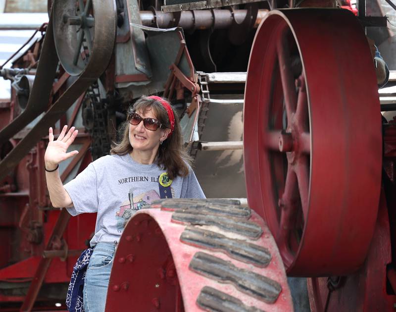 Julie Atkinson, from Hampshire, waves at parade watchers from a steam powered tractor Thursday, Aug. 7, 2025, at the 68th annual Sycamore Steam Show and Threshing Bee at Taylor Marshall Farm on Lukens Road in Sycamore.
