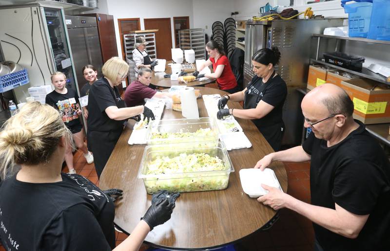 Volunteers place salad, bread and desert into to-go containers during the Lighted Way spaghetti dinner on Monday, April 28, 2025 at Uptown Bar & Grill downtown La Salle.