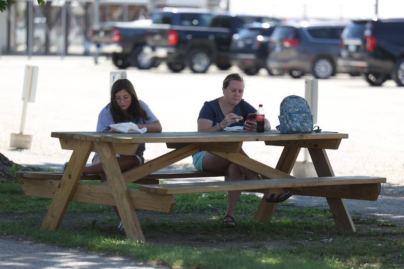 Calista Nebel, left, and Mary Wilson find a shady spot to eat at the Grundy County 4-H Fair on Sunday, July 30 in Morris.