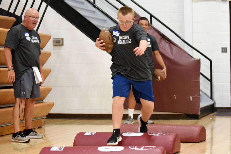 Evan Hudson, right, runs through a drill as Watseka assistant football coach John Anderson looks on during the school's Tackling Disabilities football camp Saturday, July 26, 2025.