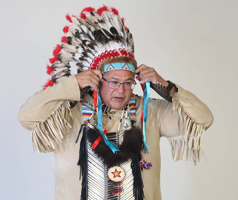 Chief Gerald Savage puts on his American Eagle feather bonnet during a presentation to students at Illinois Valley Community College on Wednesday, Nov. 2, 2022 in Oglesby,. Chief Savage, was an IVCC graduate and lived across from Starved Rock Lodge. Chief Savage shared stories of native Americans in the Illinois Valley and beyond. The program was in honor of Native American History Month.