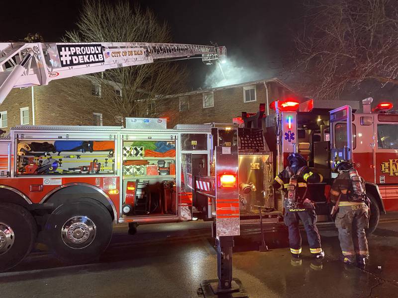 Two DeKalb firefighters don their gear as they prepare to join the crews fighting a multi-building apartment fire on Sunday, Dec. 22, 2024, in the 1000 block of West Hillcrest Drive in DeKalb.