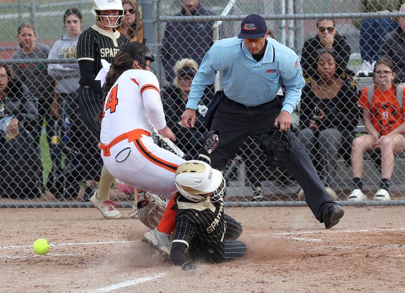 Sycamore's Delaney Larson scores on a wild pitch as DeKalb's Jasmine Rodriguez covers the plate Friday, May 2, 2025, during their game at DeKalb High School.