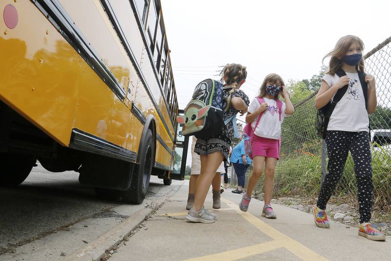 Students hop off the bus to be welcomed back to school by staff on their first day back at Landmark Elementary School on Wednesday, July 21, 2021 in McHenry.  The school, which has about 210 students, offers a shortened summer break but extended fall and winter breaks to make the educational process more year-round.