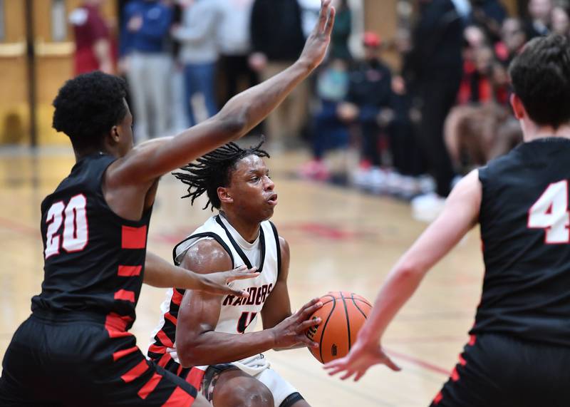 Kevin Cathey looks to pass as Benet's Ewola Moukoulou (20) and Patrick Walsh defend during a Class 4A East Aurora Sectional semifinal game on Feb. 27, 2024 at East Aurora High School in Aurora.