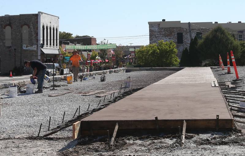 Crews finish pouring a new stamped sidewalk near the retail plaza site on Tuesday, Oct. 8, 2024 downtown Utica.