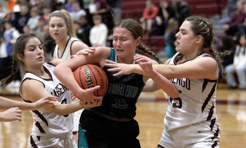 Marengo’s Emilie Polizzi, right, and Keatyn Velasquez, left, battle Woodstock North’s Adelynn Saunders in varsity girls basketball at Marengo Tuesday evening.