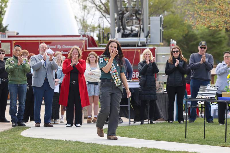 Alexis McCullough, 17, of Bourbonnais, wipes away a tear as her mother, Cassandra, at left, applauds with the crowd as she is introduced to speak at the dedication ceremony for the new Gold Star Families Memorial Monument in Bourbonnais, which she successfully completed for her Eagle Scout project, on Saturday, April 26, 2025.