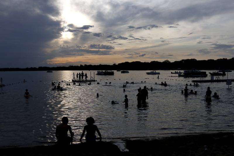 People enjoy the waters of Crystal Lake during the Crystal Lake Park District's Concert in the Park on Tuesday, June 17, 2025, at Main Beach in Crystal Lake. The concert was part of the park district's weekly Tuesday night summer concert series.