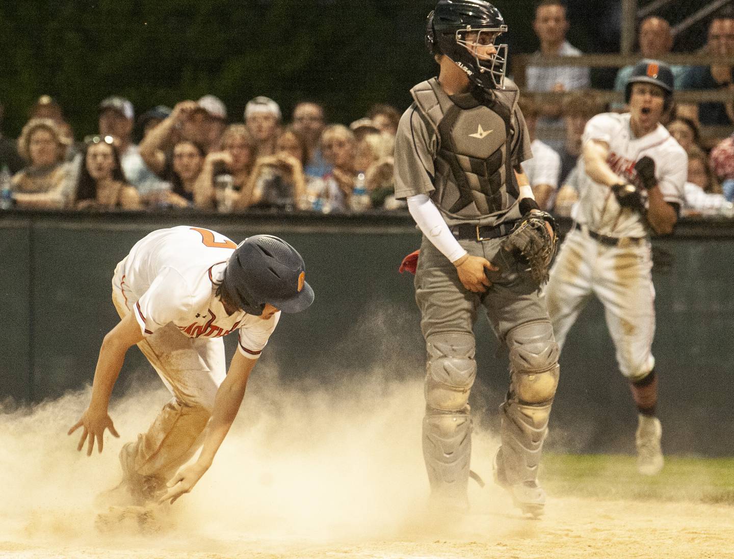 Dylan McGee (7) scores Oswego's 5th run, as Oswego East catcher Eric Lewis can only watch as a teammate retrieves an errant throw to the plate, during a varsity boys baseball game on Thursday, May12, 2022 at Oswego High School.