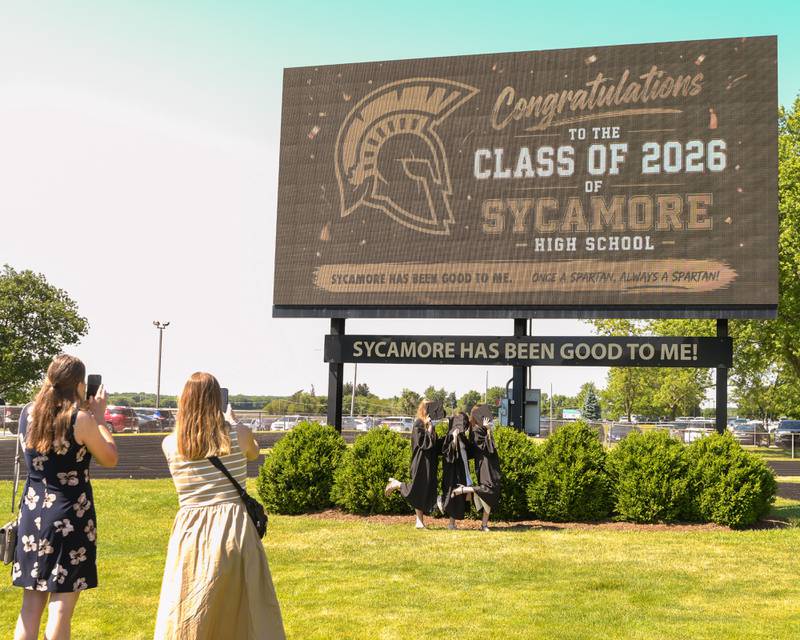 Sycamore High School graduates (from left) Ashley Tucker, Natalee Hernandez and Julia Peska pose for a photo in front of the football field scoreboard after the Class of 2026 Commencement on Sunday, May 24, 2026, at Sycamore High School.
