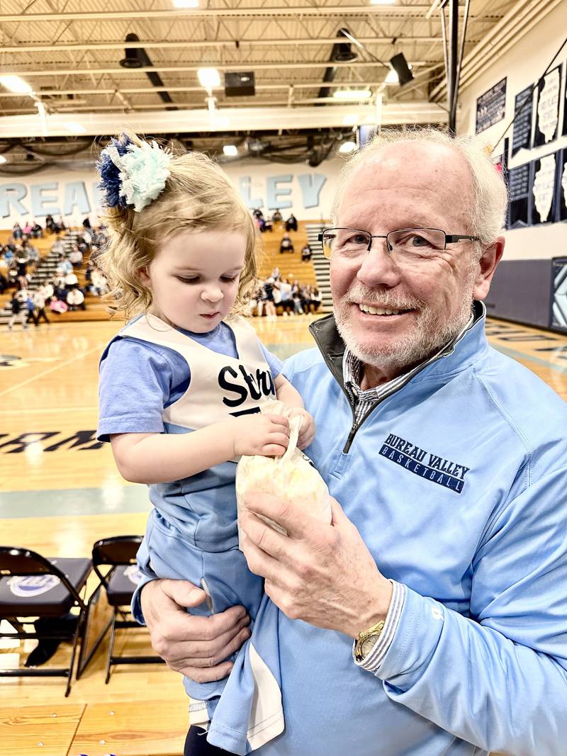 Roger Bolin holds his granddaughter, Tessa, during a Bureau Valley basketball game. The step father of coach Jason. Marquis, Bolin was a fixture at Storm basketball games as the official scorer. He came into the Storm coach's life when Marquis was in the third grade and immensely impacted his life. Roger passed away on Jan. 1 at 71 years old.