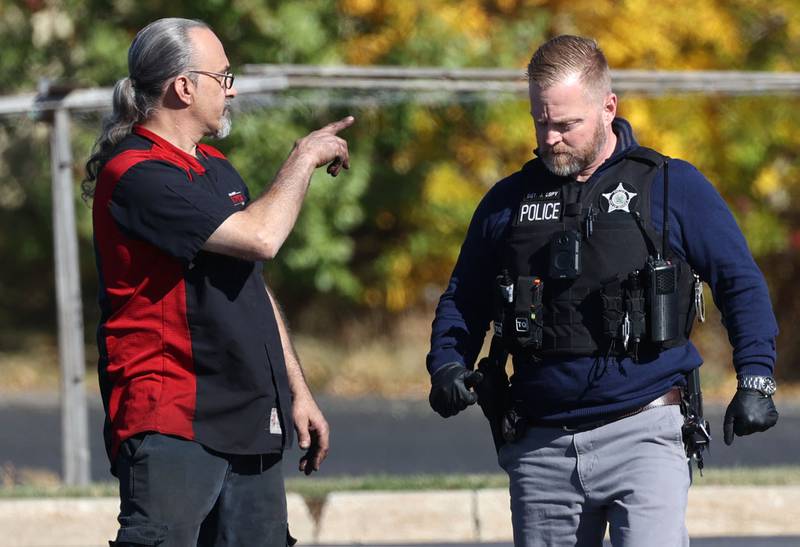 A DeKalb Police officer talks to a Brian Bemis Toyota employee Wednesday, Oct. 23, 2024, outside the dealership in DeKalb after responding to a stabbing where multiple employees were injured. The incident ended after police shot the man wielding the knife authorities said.