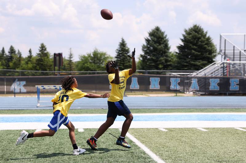 Justice Bogan, 9, left, of Bradley and Travis Brown, 10, of Calumet City, compete for a pass during the Suga Summer Camp at Kankakee High School on Saturday, July 5, 2025.