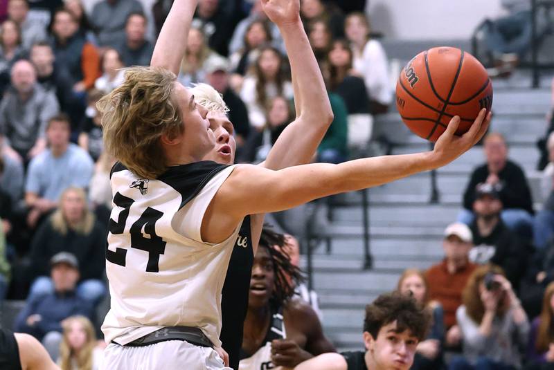 Kaneland's Luke Reinert scores and is fouled by Sycamore's Aidan Wyzard during their game Friday, Jan. 5, 2024, at Kaneland High School in Maple Park.