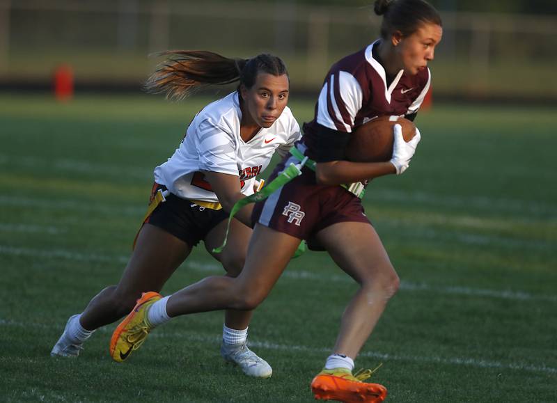 Prairie Ridge’s Lila Stewart runs with the ball as Crystal Lake Central's Amelia Smith tries to grab her flag during a girls flag football game on Thursday, Sept. 4, 2025, at Prairie Ridge High School in Crystal Lake.