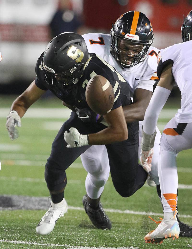 DeKalb's Michael Newman forces Sycamore's Manuel Dominguez to fumble Friday during their game at Northern Illinois University's Huskie Stadium. The teams were playing in this season's edition of the First National Challenge, a fundraiser hosted by First National Bank that benefits the Booster Clubs of both schools.