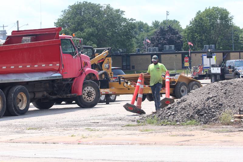 A worker carries construction cones at site of the Utica retail plaza on Monday, July 15, 2024 near the intersection of Mill and Grove Streets. Workers poured a sidewalk and have started the preliminary work on the Market on Mill area. The project is scheduled to be completed just before Burgoo.