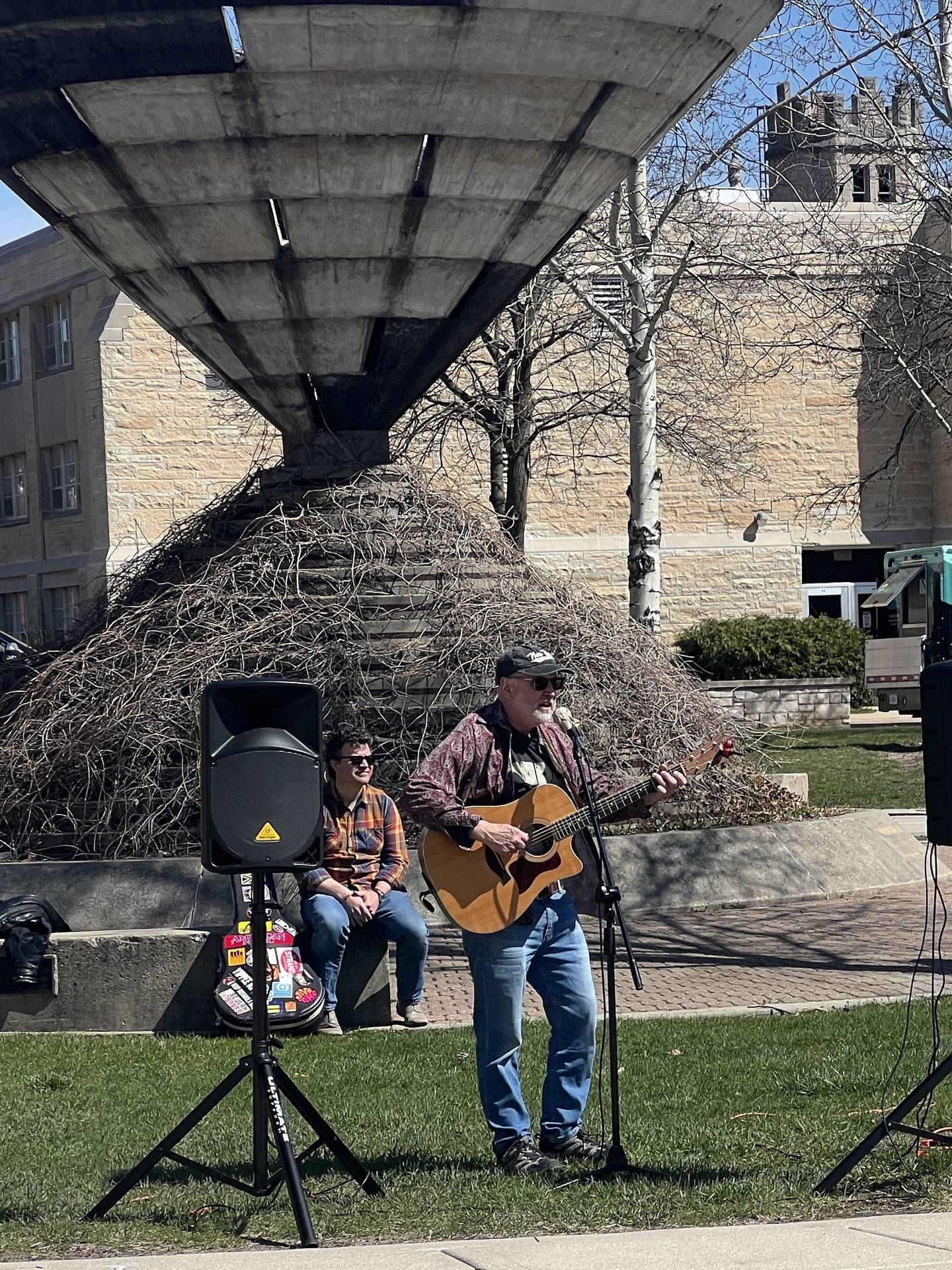 Mike Warfel and Gibson Cima, who was seated behind Warfel, performed on NIU's campus on April 8, 2026, as a part of a union-led rally for the Adequate and Equitable Public University Funding Act
