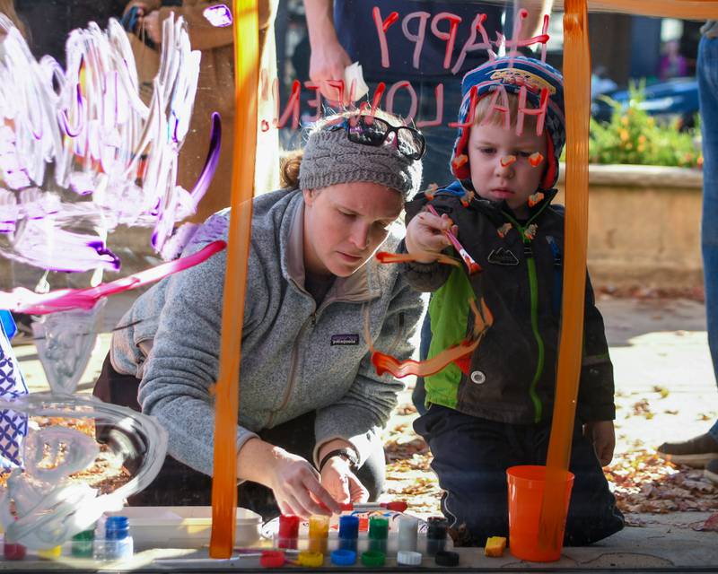 Helen Daly and her son Connor Daly, 4, of Downers Grove paint a window on Saturday Oct. 26, 2024, during the Halloween event in downtown Downers Grove.
