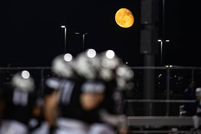 Plainfield North huddles under the moon during a game against Joliet West  Friday Sept. 20, 2024 at Plainfield North High School