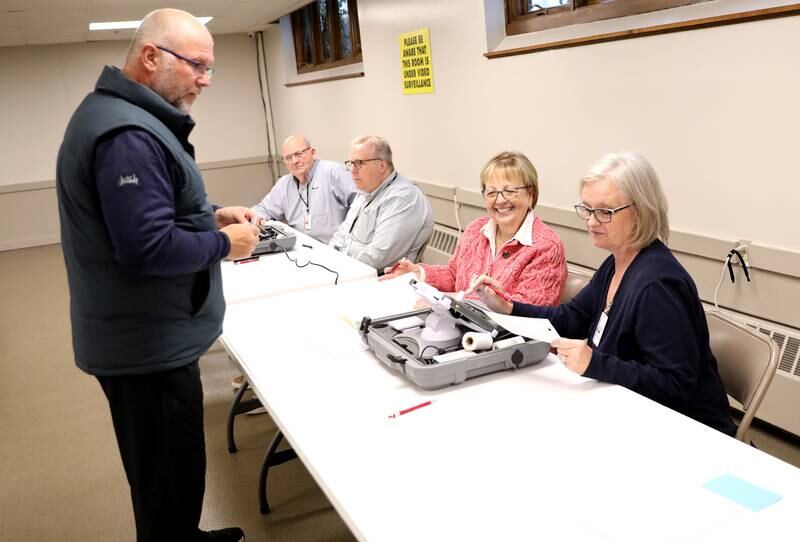 Election judges Debbie Cloke and Sandy Ledesma assist voter Tim Betustak in the 2025 Consolidated Election on Tuesday, April 1, 2025 at the Sugar Grove Township Community Building in Sugar Grove.