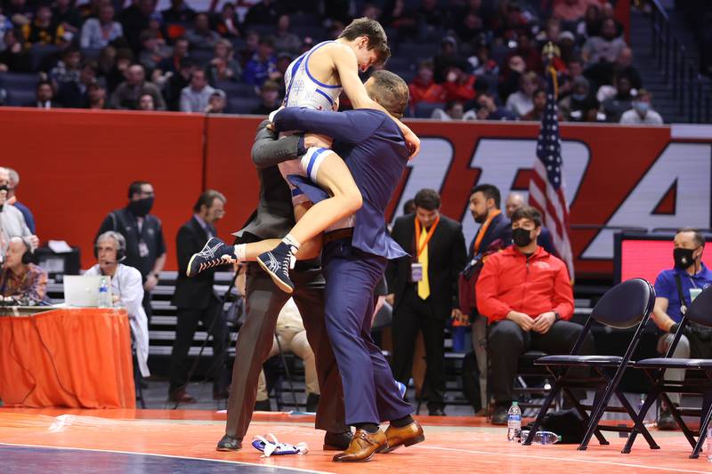 Marmion’s Jameson Garcia jumps into the arms of his coaches after his win over Mt. Carmel’s Damian Resendez in the Class 3A 113lb. championship match at State Farm Center in Champaign. Saturday, Feb. 19, 2022, in Champaign.