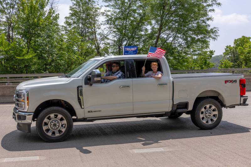 Josiah Assell waves the American flag from his father's truck which was participating in the Trump Birthday and Flag Day Caravan and Rally on June 14, 2025 in Ottawa.