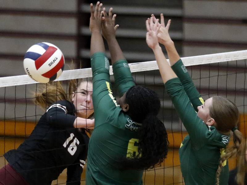 Prairie Ridge's Addy Grider (left) hits the ball past the block attempt of Crystal Lake South's Sahara Okirika (center) and Nora Wiggs (right) during the IHSA Class 3A Prairie Ridge Regional championship volleyball match on Thursday, Oct. 30, 2025, at the Prairie Ridge High School in Crystal Lake.